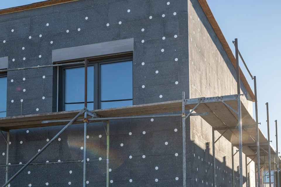 Gros plan professionnel montrant des matériaux de qualité supérieure pour isolation thermique par l'extérieur : panneaux isolants modernes avec finitions haut de gamme, système de fixation professionnel, et document de garantie décennale visible à côté. La composition doit transmettre la solidité, la durabilité et l'excellence des matériaux utilisés par CAN Isolation.