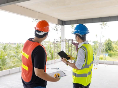 Réunion professionnelle sur un chantier de construction entre l'architecte et les artisans qui portent un masque de protection contre le vid-19