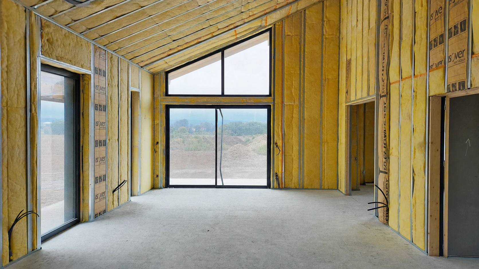 Ouvrier en combinaison bleue et masque respiratoire installant de l'isolation thermique dans les combles d'une habitation