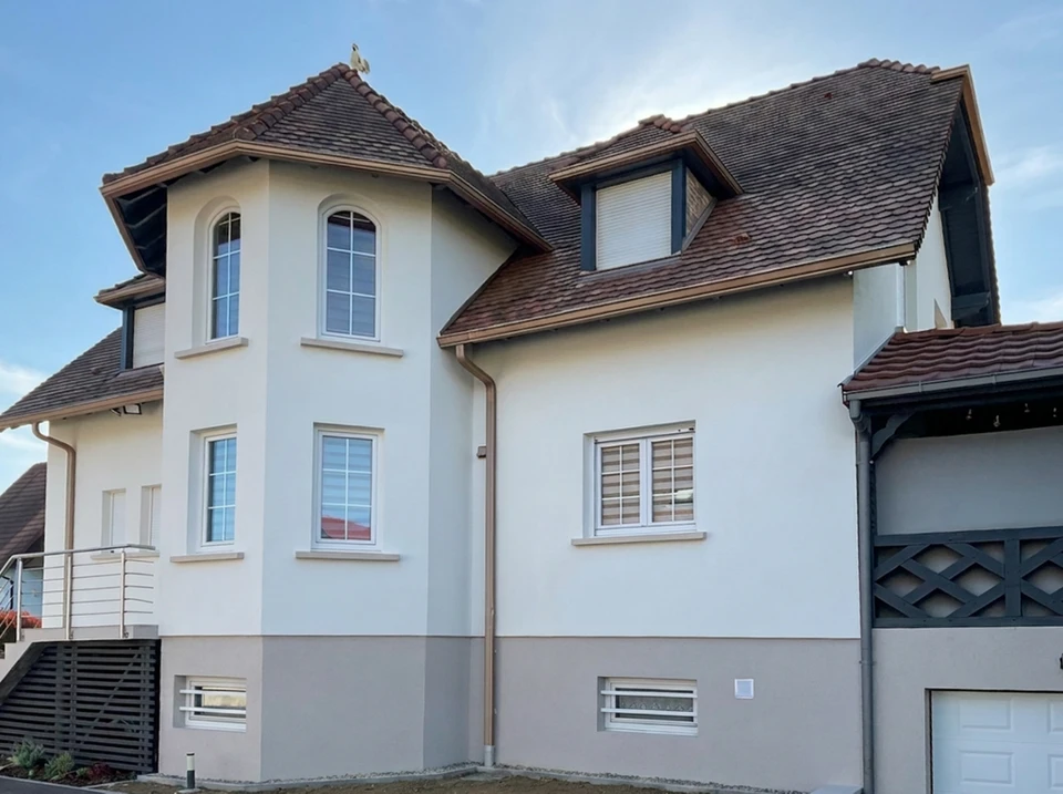 Ouvrier peignant un mur extérieur, appliquant de la peinture blanche sur une surface bleue avec un rouleau