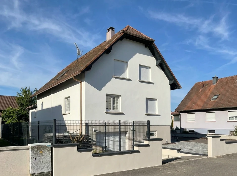 Façade de bâtiment résidentiel avec deux fenêtres à volets battants verts ouverts, encadrements blancs sur mur ocre